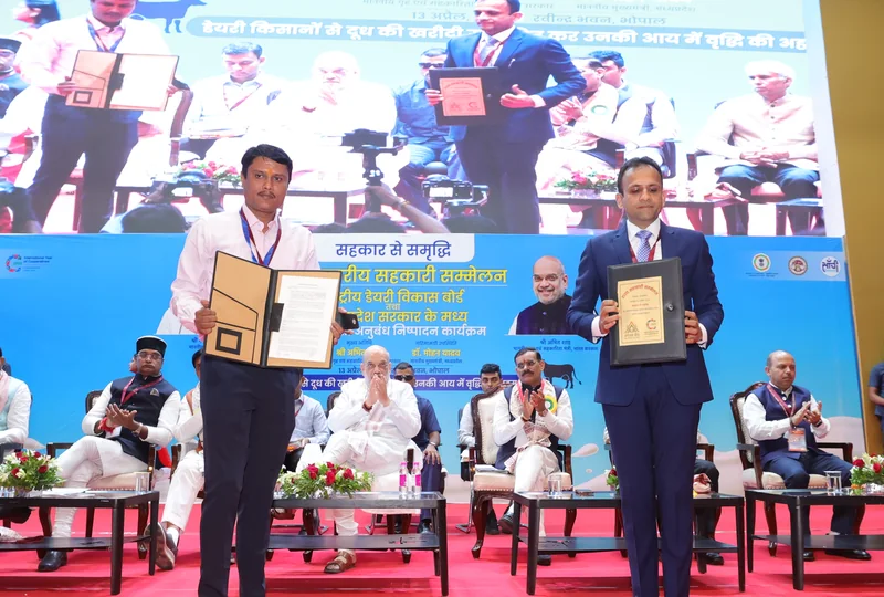 भोपाल के सहकारिता सम्मेलन के मंच पर अधिकारी समझौते के दस्तावेज दिखाते हुए